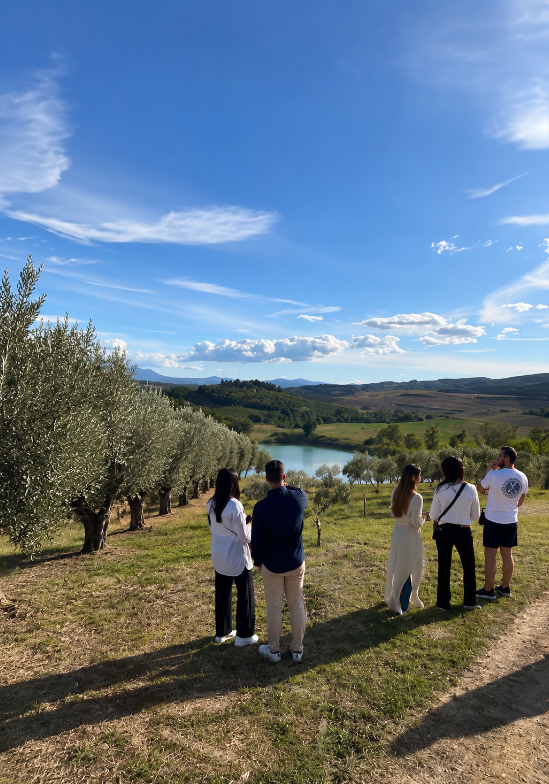 Comunidad Oria contemplando el paisaje de olivos y lago en Val d'Orcia
