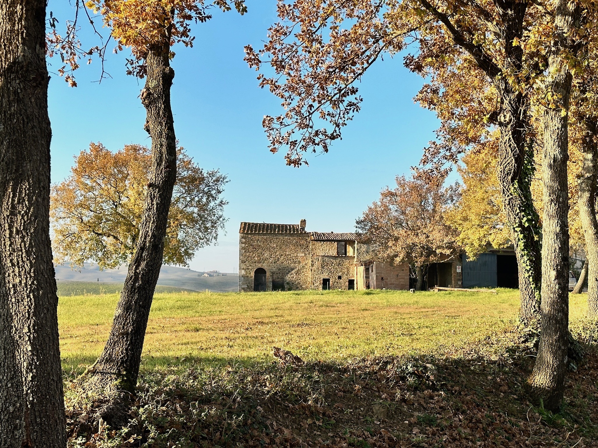 Finca Oria en otoño — piedra toscana del siglo XVI entre robles y colinas del Val d'Orcia